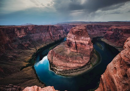 large rock formations with a circular water-filled canyon carved into it
