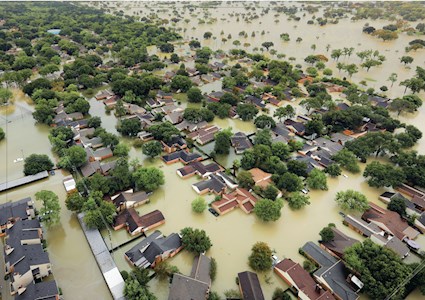 aerial photo of flooded neighborhood with partially submerged homes and trees and fully submerged streets