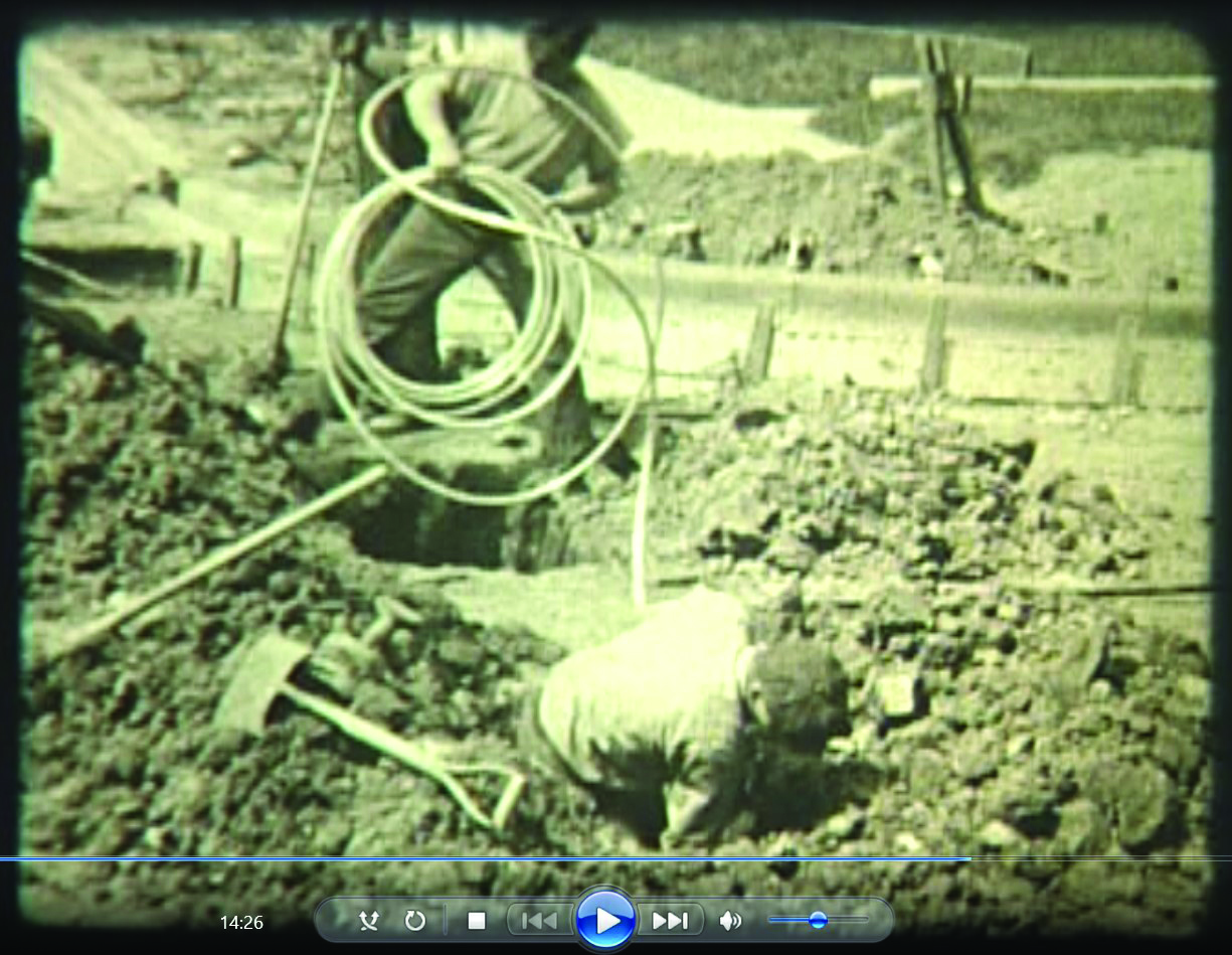 frame from a movie showing a man digging in a hole