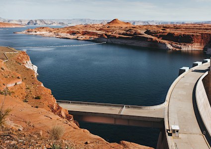 concrete dam full of water surrounded by dry landscape