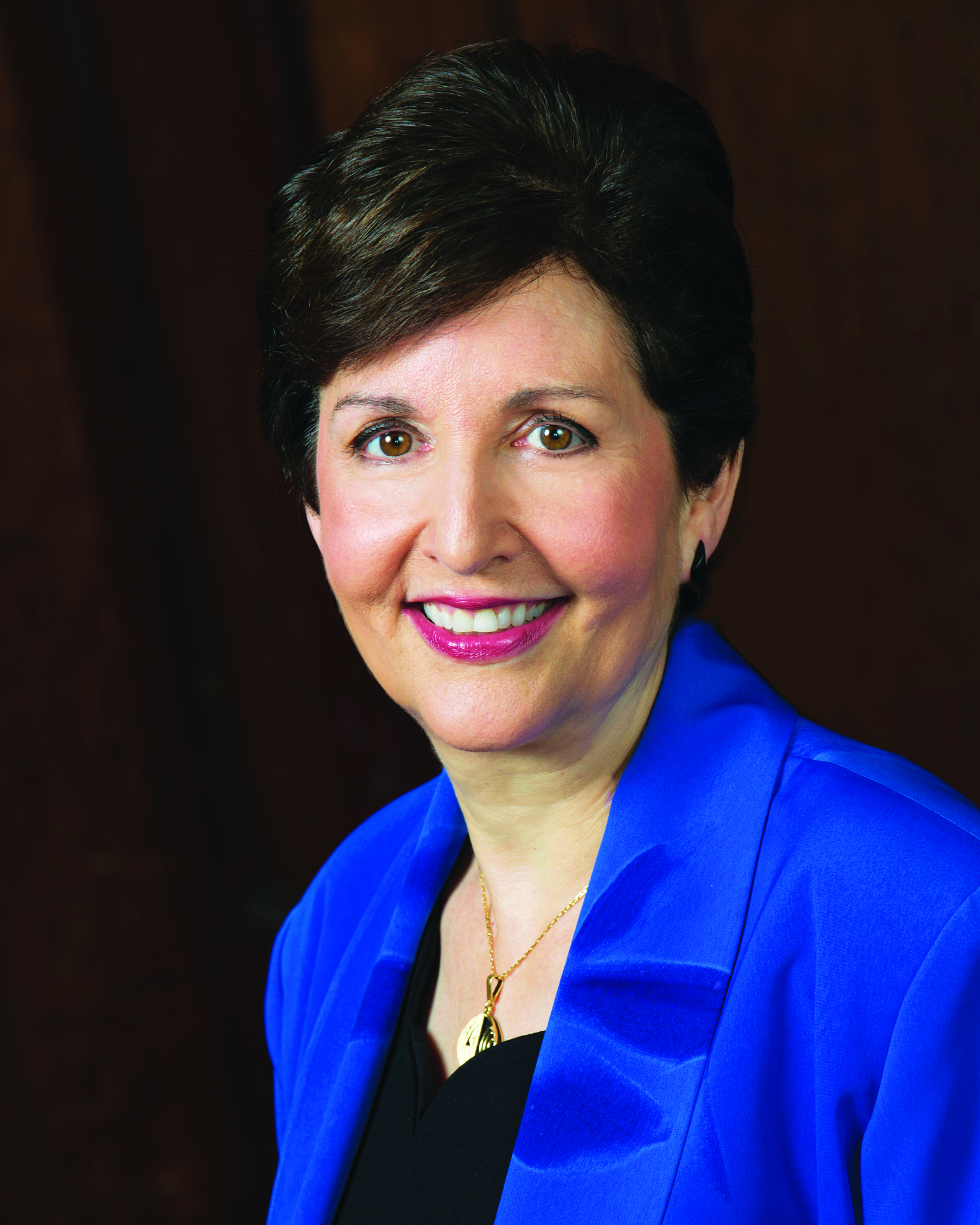 white woman with short brown hair wearing a purple jacket and black top