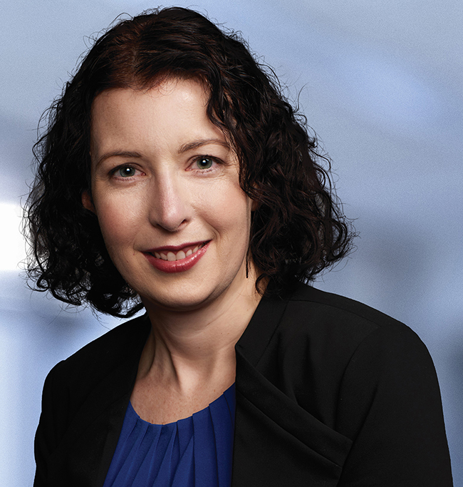 woman with dark brown curly hair smiling at the camera