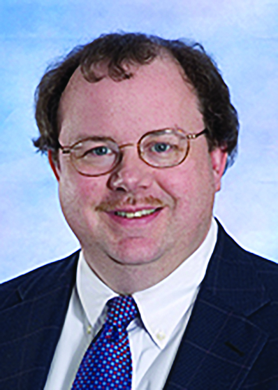 white male with short curly hair and glasses and a mustache wearing a suit and tie