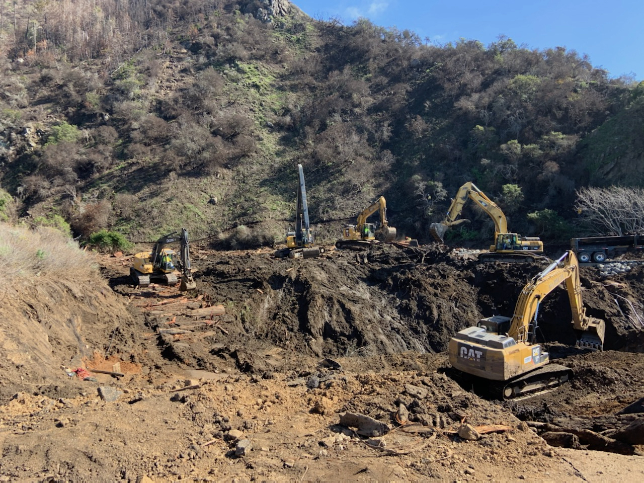 yellow machinery sits amid dried mud