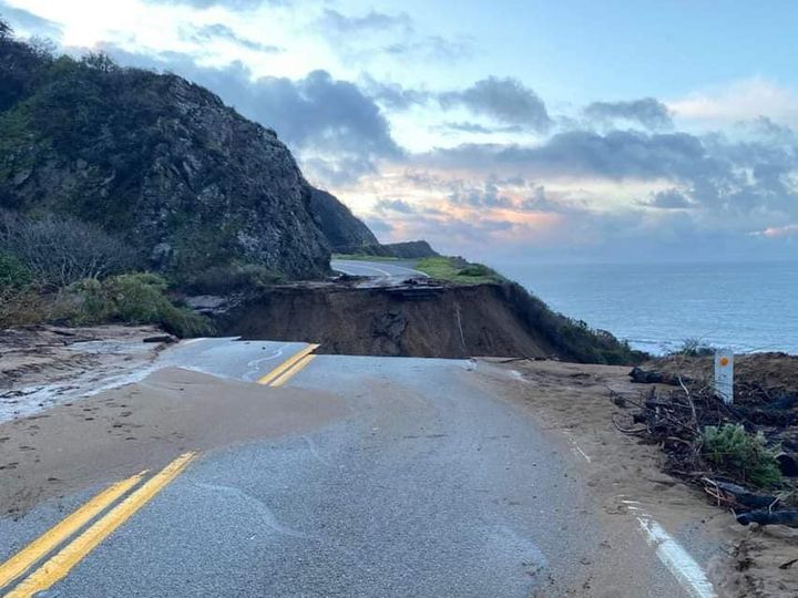 looking at a section of washed out road with the ocean and horizon on the right