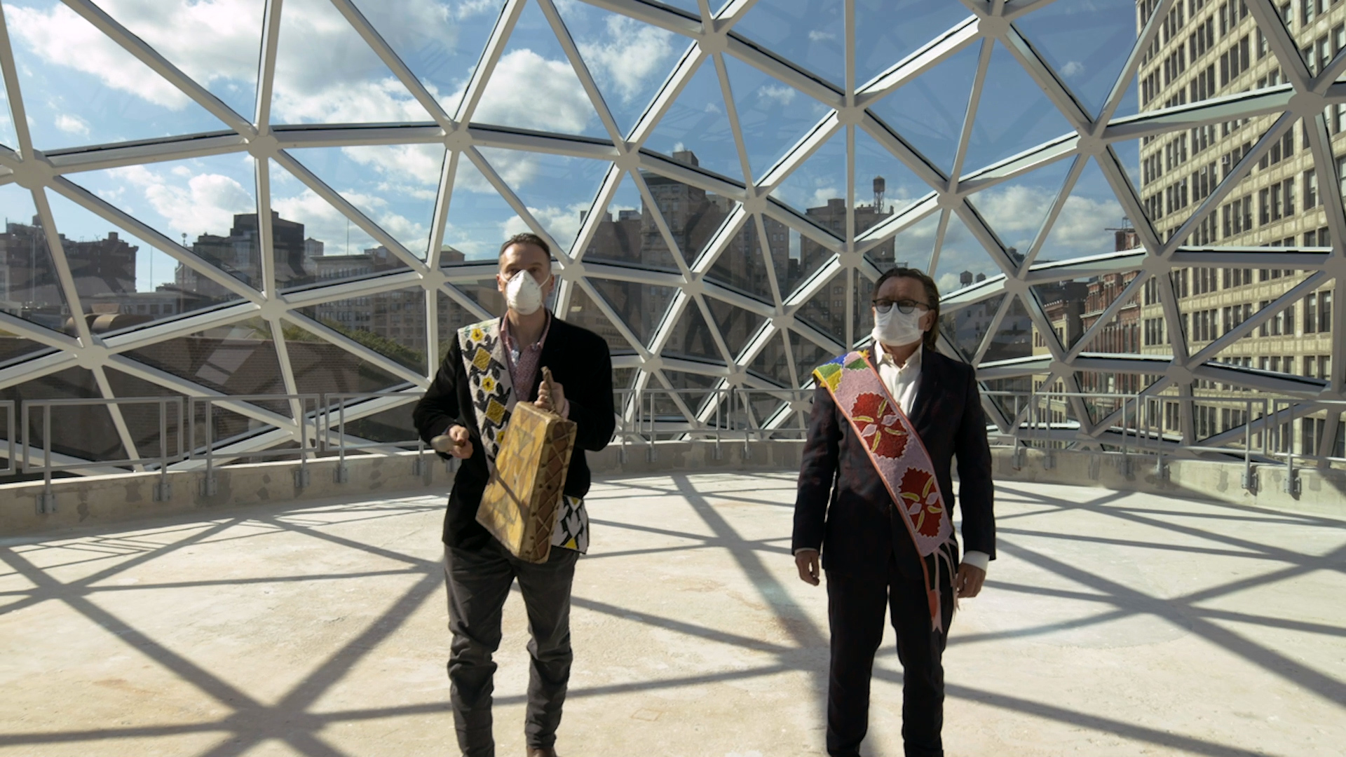 two native american men wearing masks at a dedication ceremony