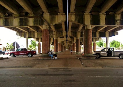 two men sit under the Claiborne Expressway