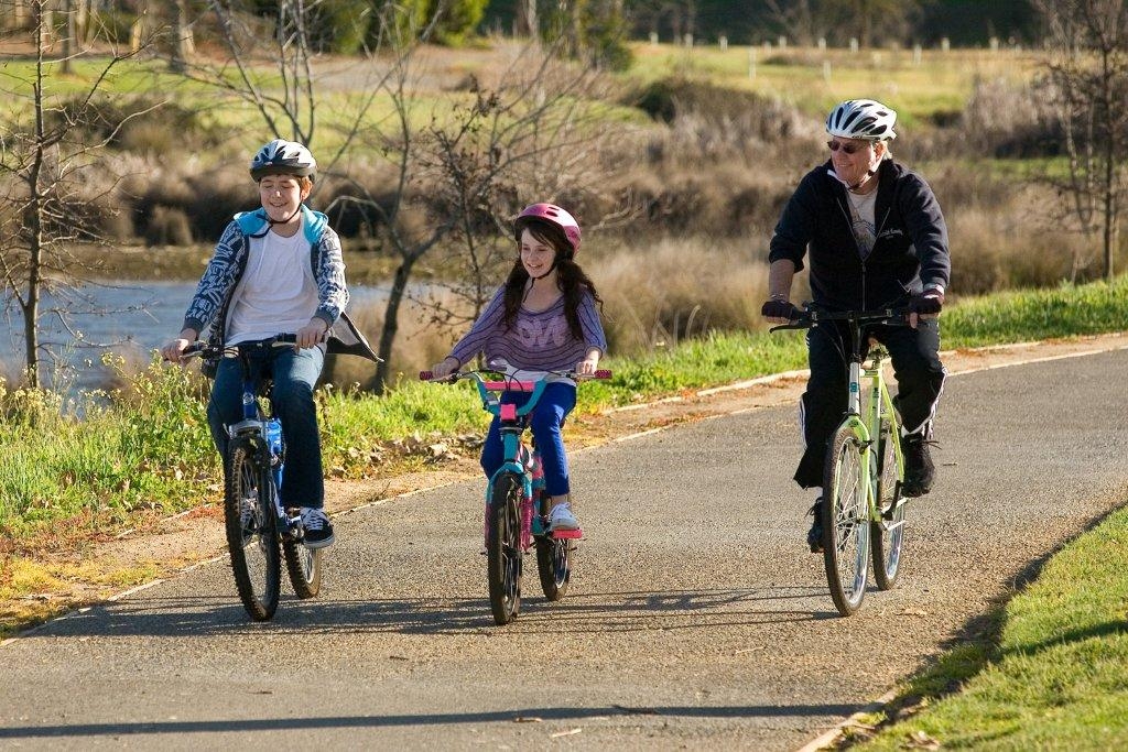 three people ride on a bikepath