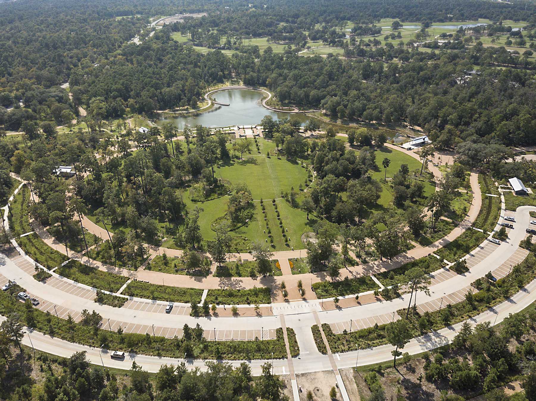 aerial shot of a park with a lake shaped kind of like an octopus and walkways, trees, and parking spaces