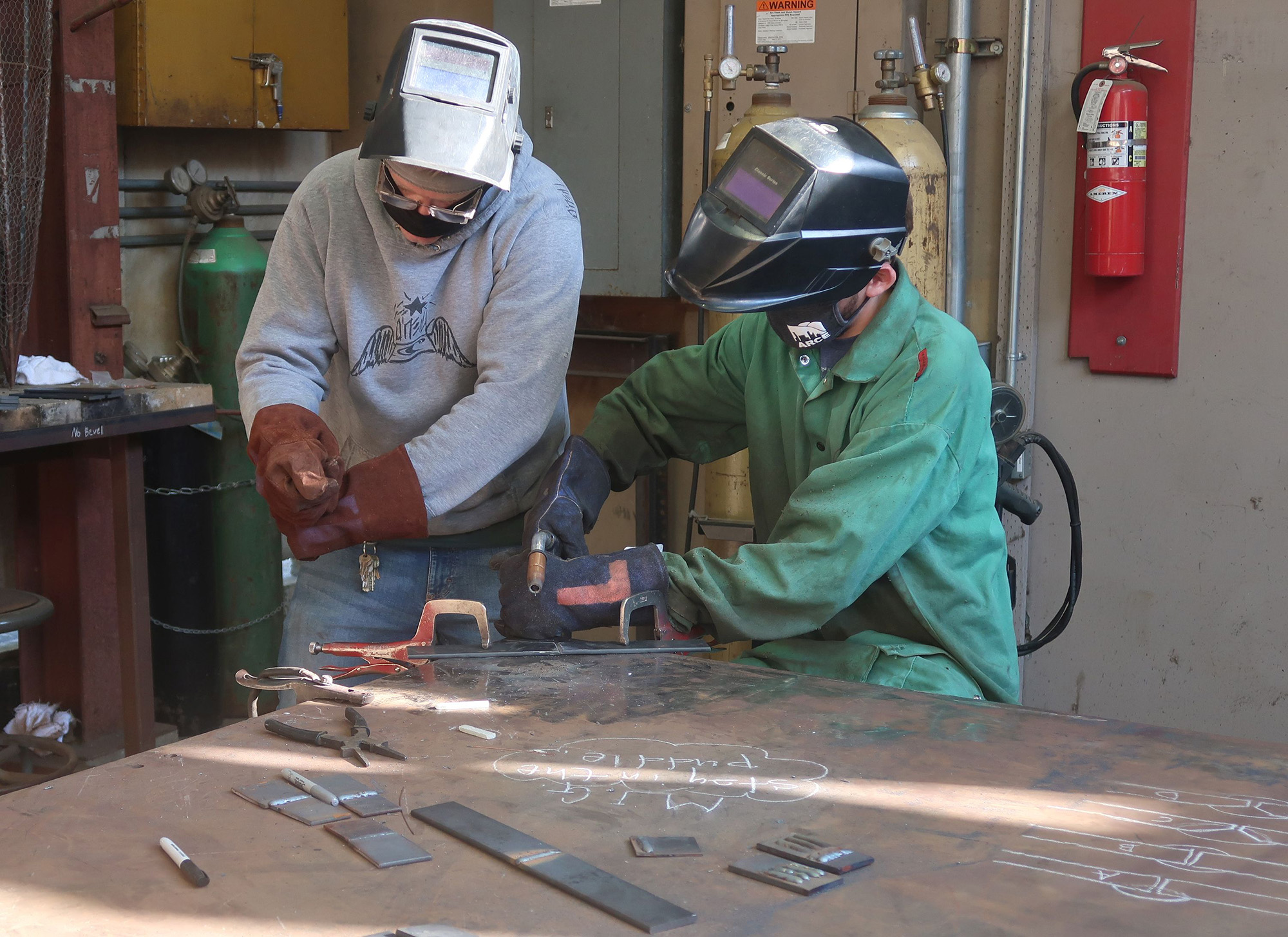 two male students are welding pieces of steel together
