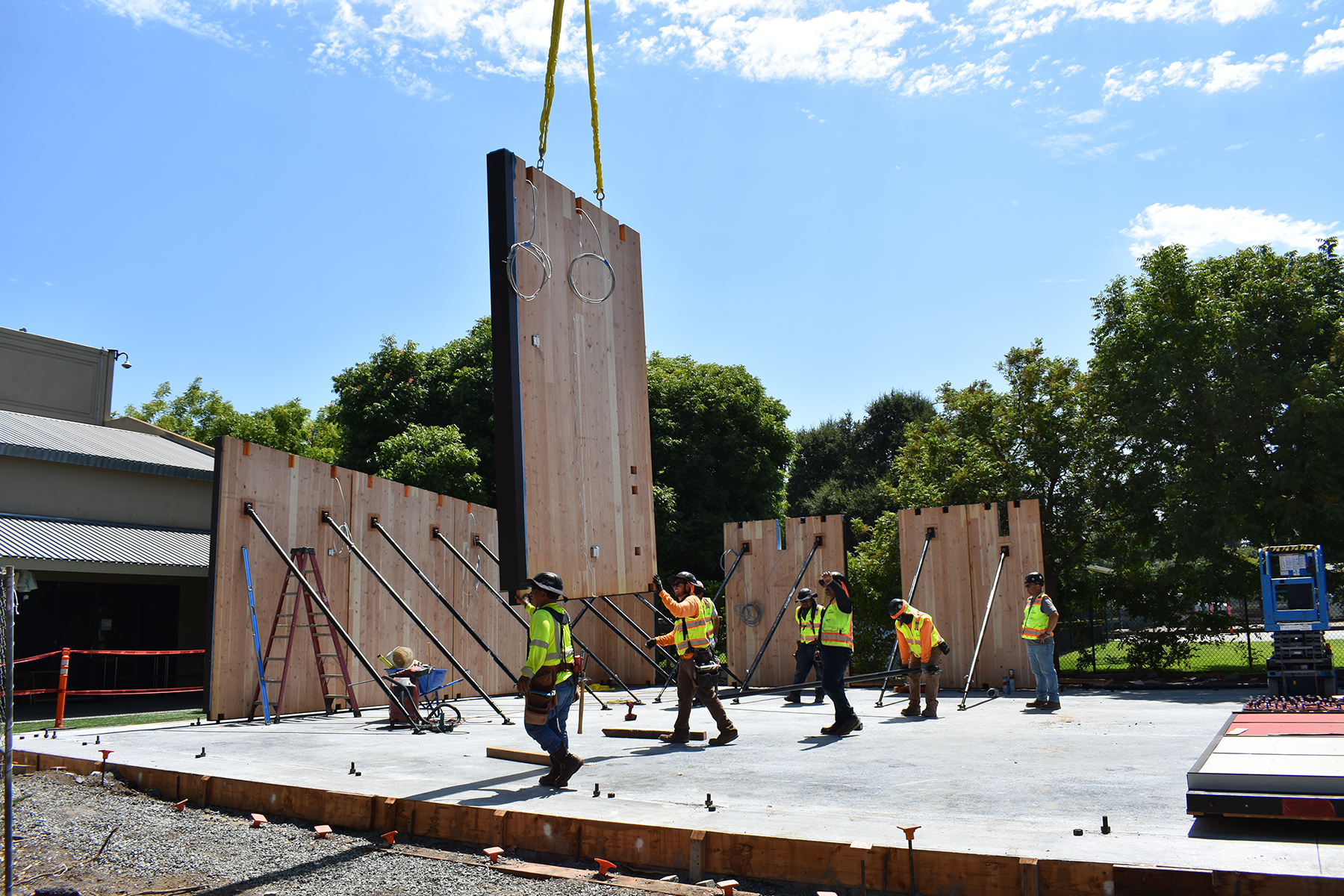 construction team lowers prefab panels into place