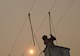 worker repairs power lines on a smoky, hazy day