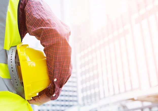 man holding yellow hard hat under his arm