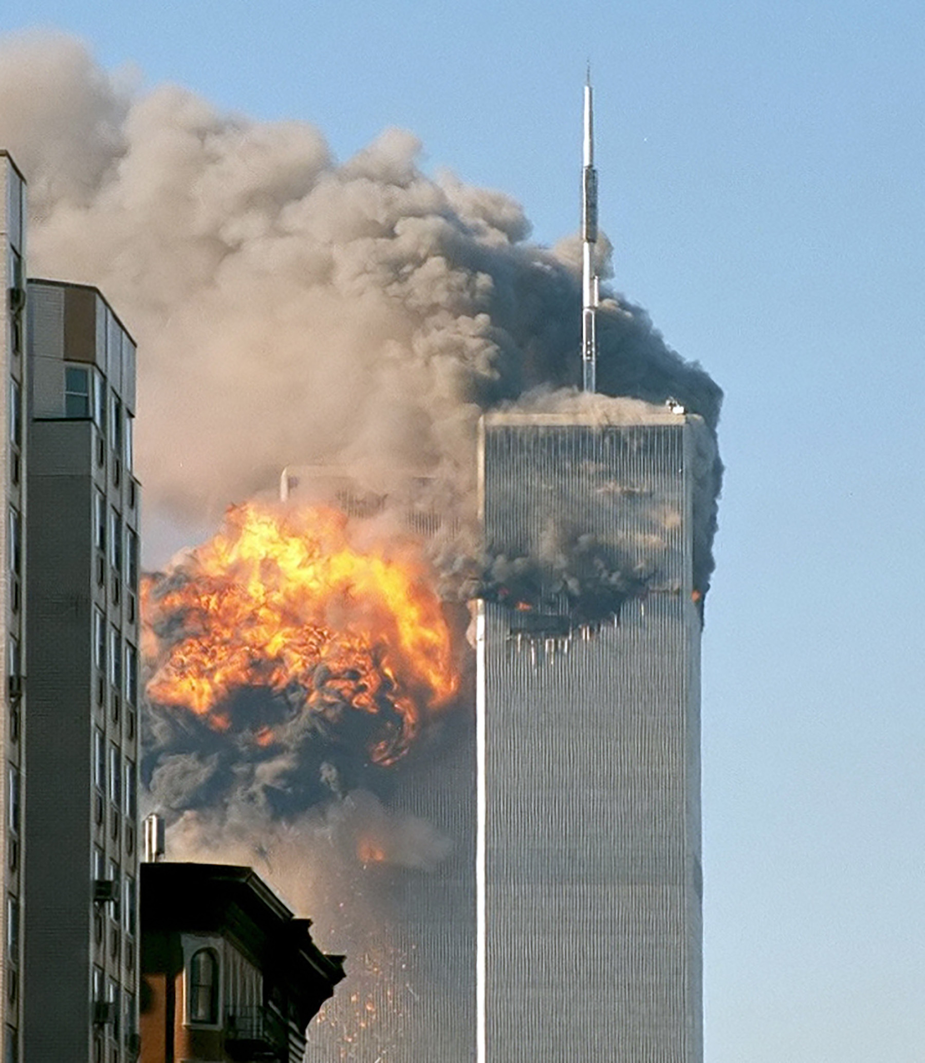 two high-rise buildings on fire. one shows the moment of plane impact. the other shows black heavy smoke billowing from it