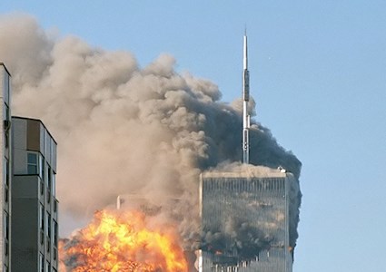 high-rise buildings on fire. one shows the moment of plane impact. the other shows black heavy smoke billowing from it
