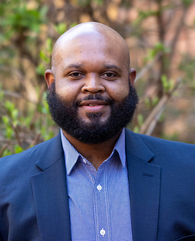 man with bushy beard in blue jacket and checked shirt