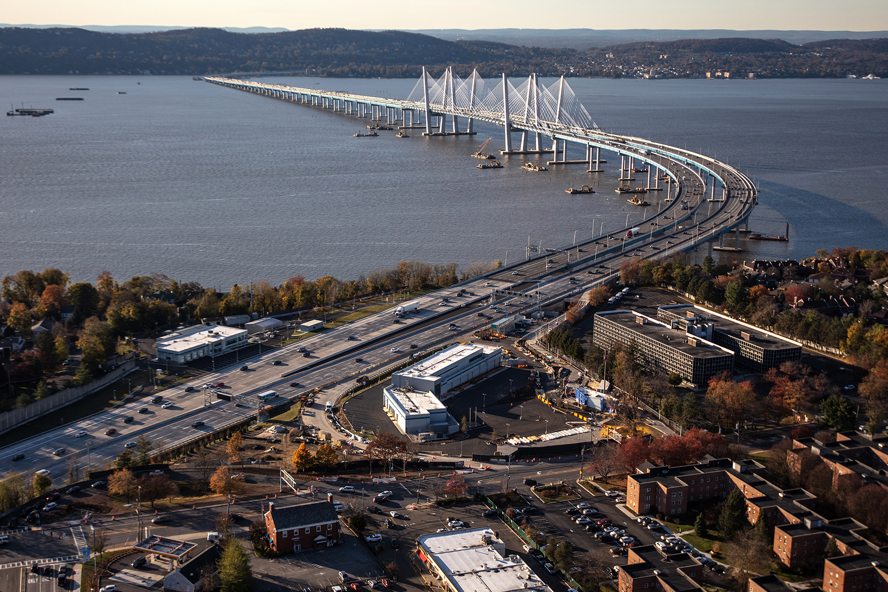 cable-stayed bridge over water with roads, trees, and cars 
