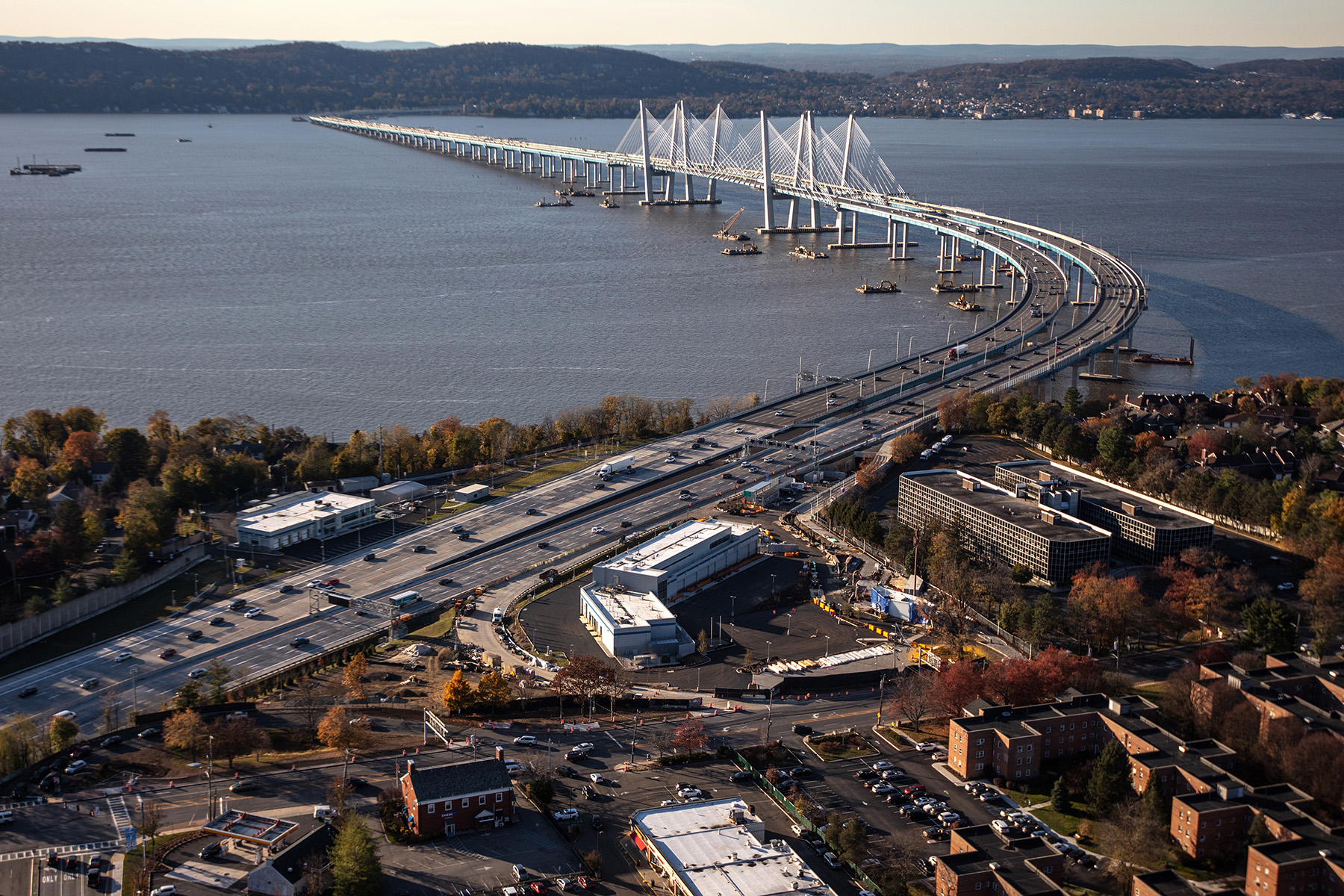 cable-stayed bridge over water with roads, trees, and cars