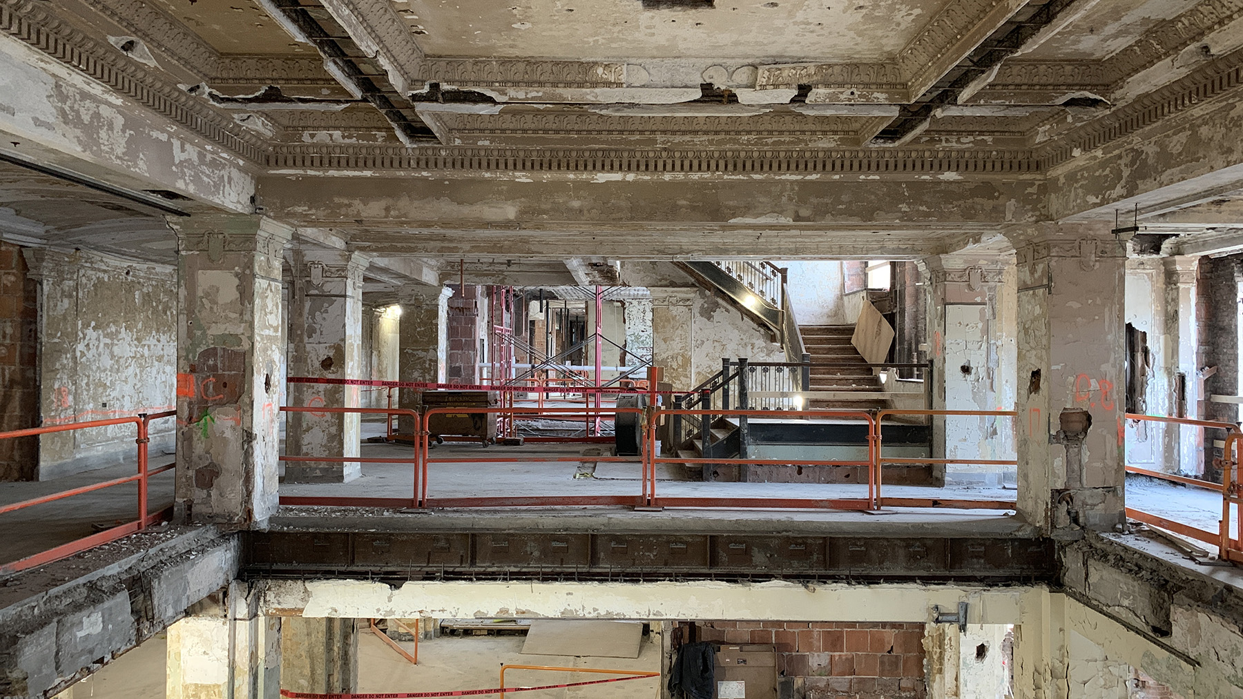 damaged stair well, plaster missing from ceiling, and parts of the floor missing in an abandoned building