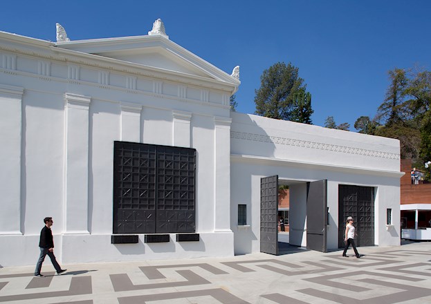 man and woman walking on patterned pavement in front of a white marble building