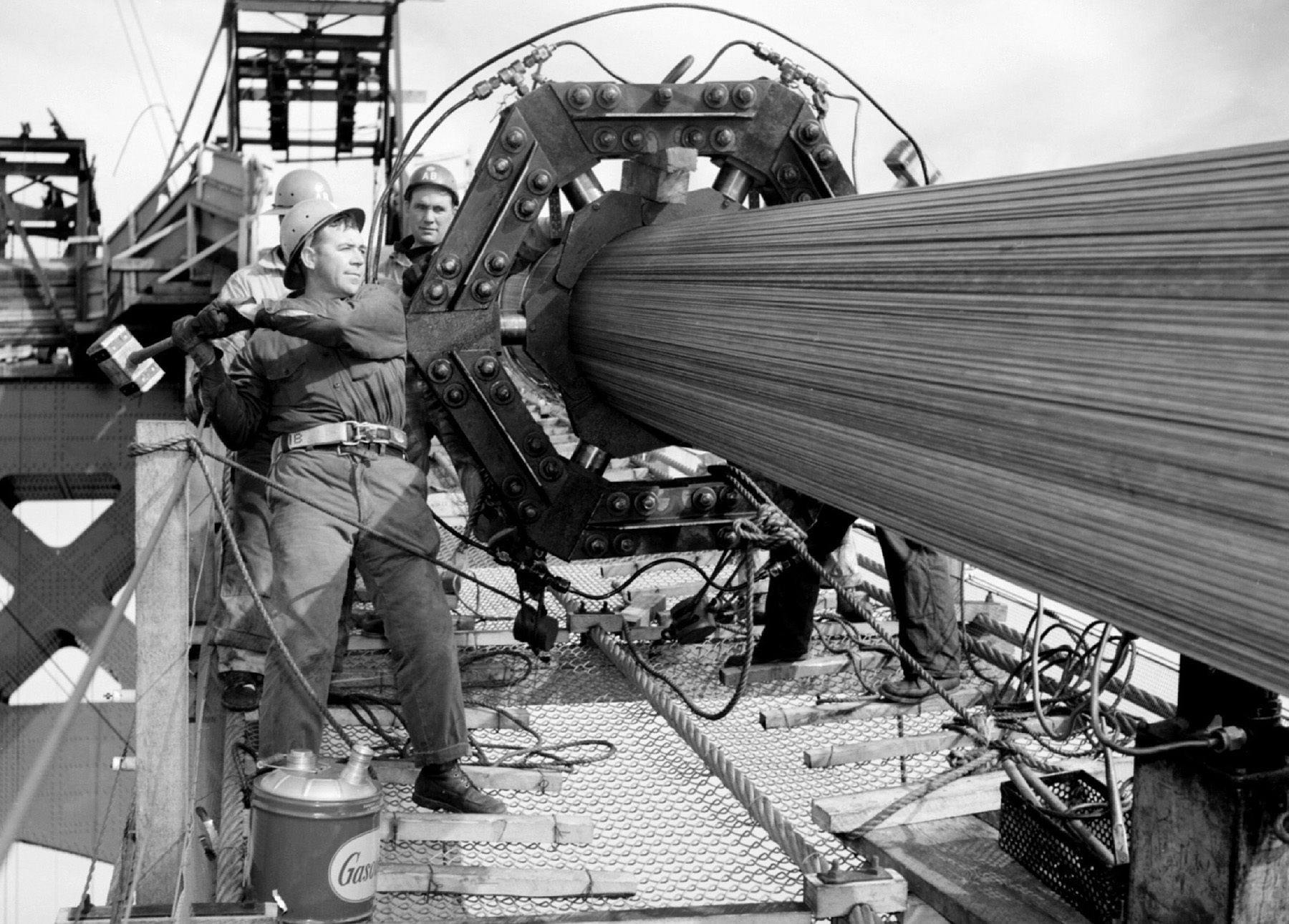 men working on a machine that compressed suspension cables