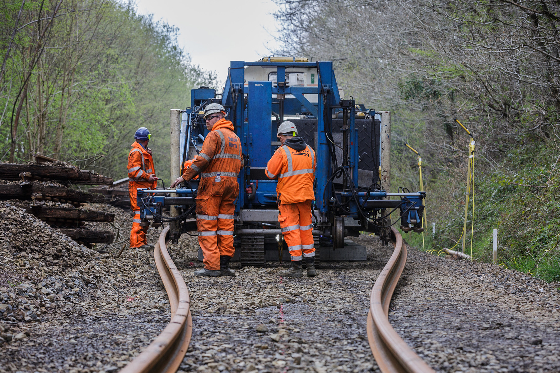 men in orange suits working on bent train track