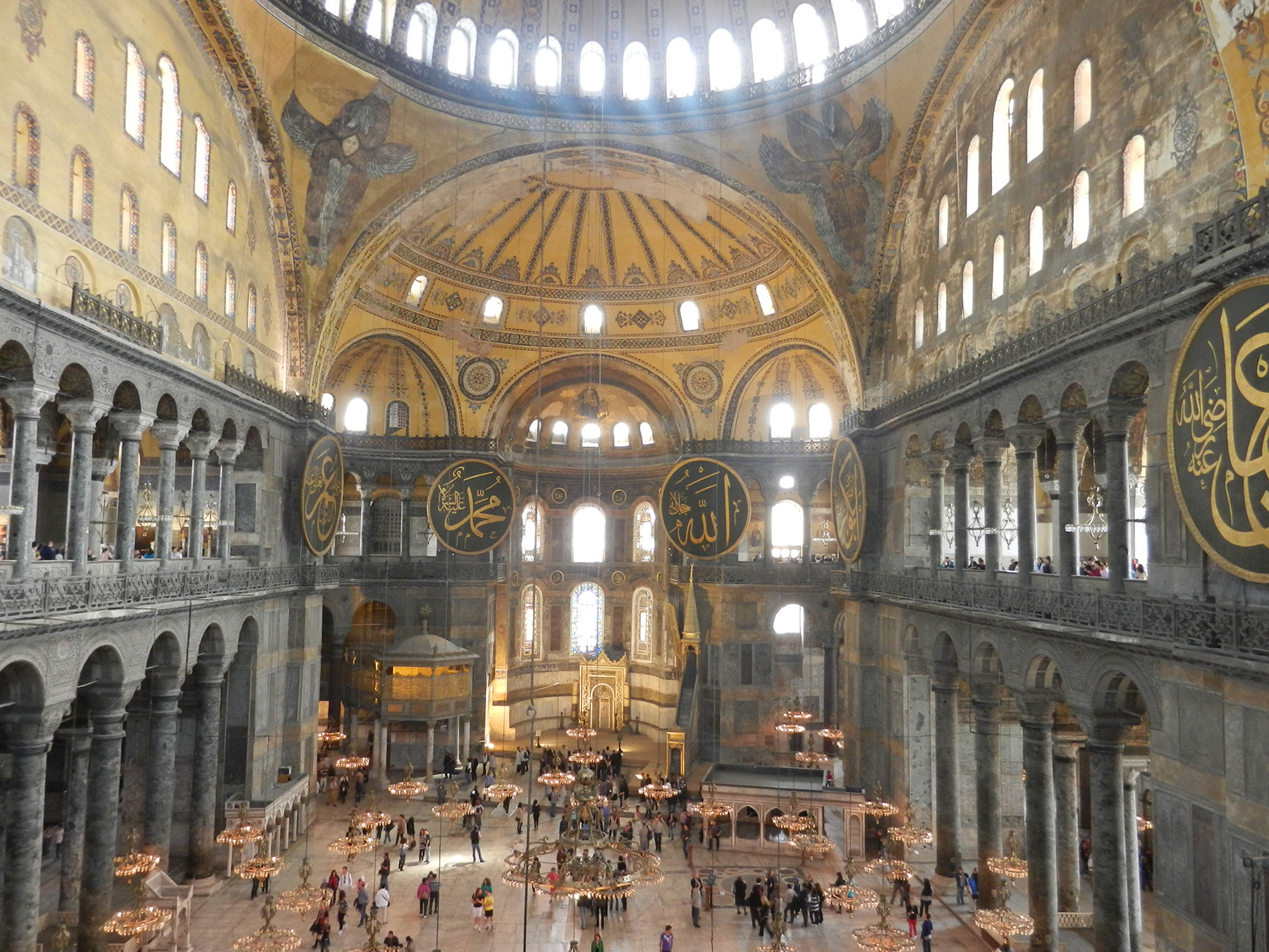 interior photo of a multistory structure with walls of windows and columns. The building is topped by a central dome that has a ring of windows that let in natural light