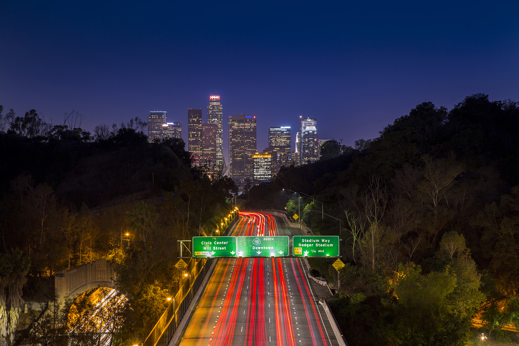 cityscape at night in the background and an interstate with lit signs in the foreground