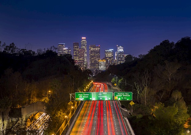 cityscape at night in the background and an interstate with lit signs in the foreground.