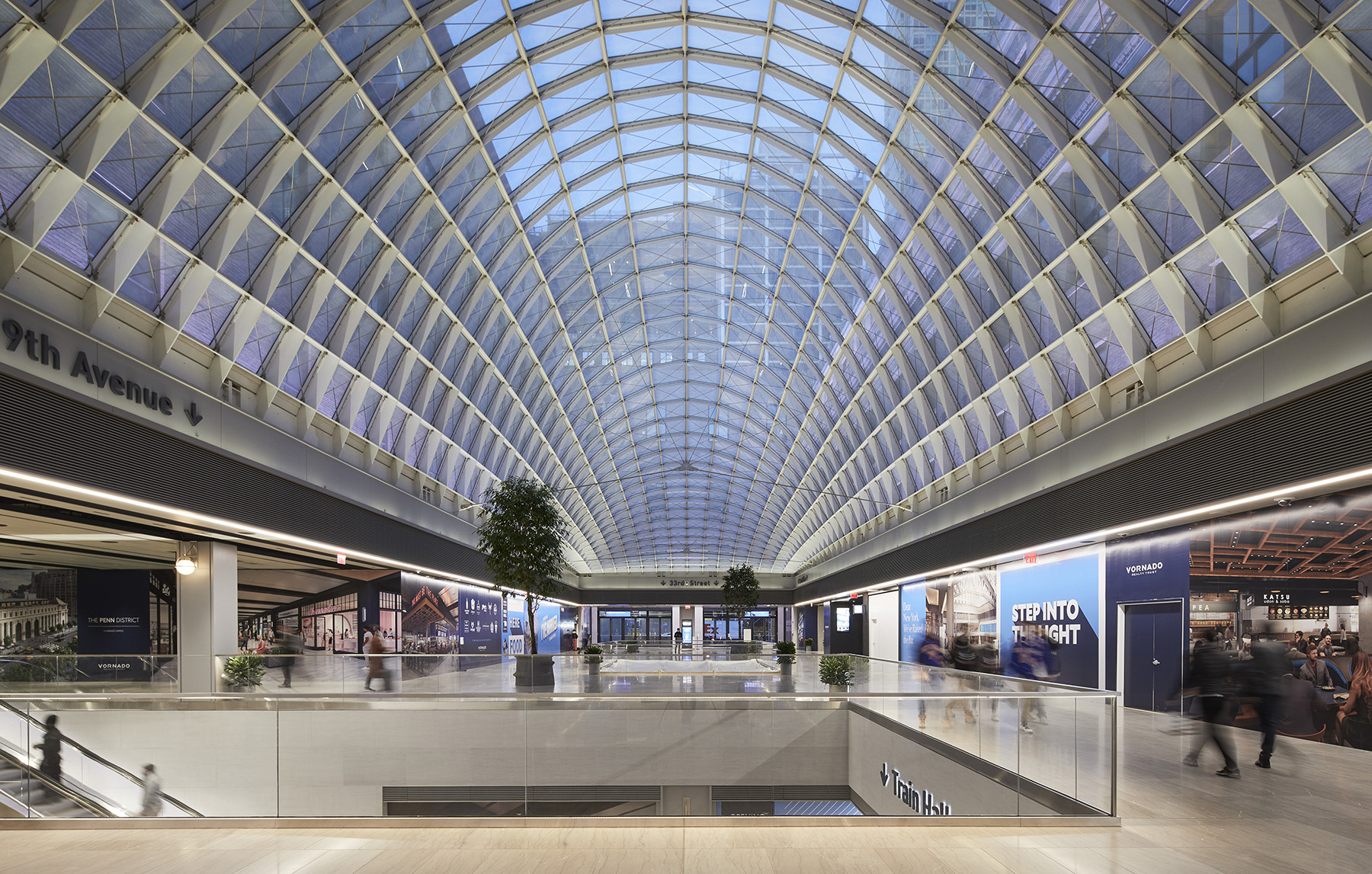 glass topped train hall with people walking and stairs leading to a lower level