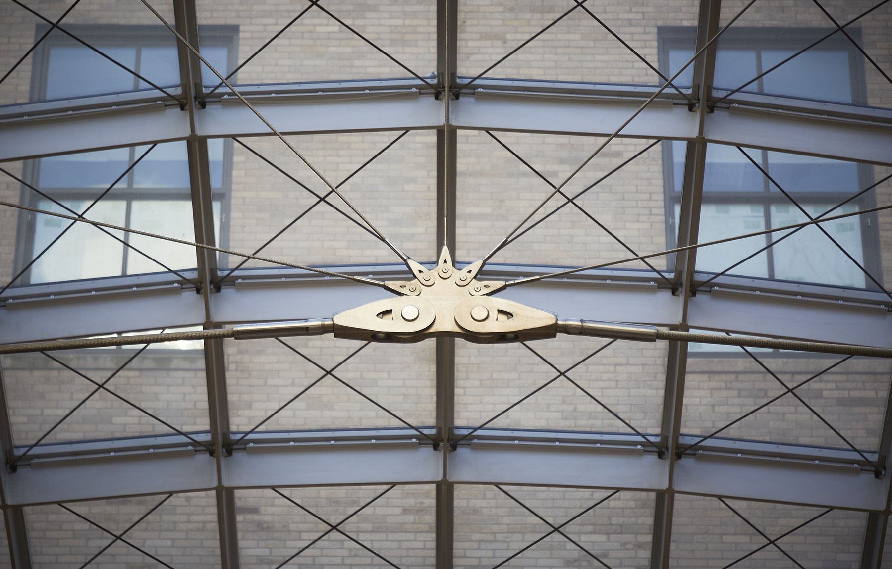 close up view of steel cables that are fixed below a skylight’s glass panels.