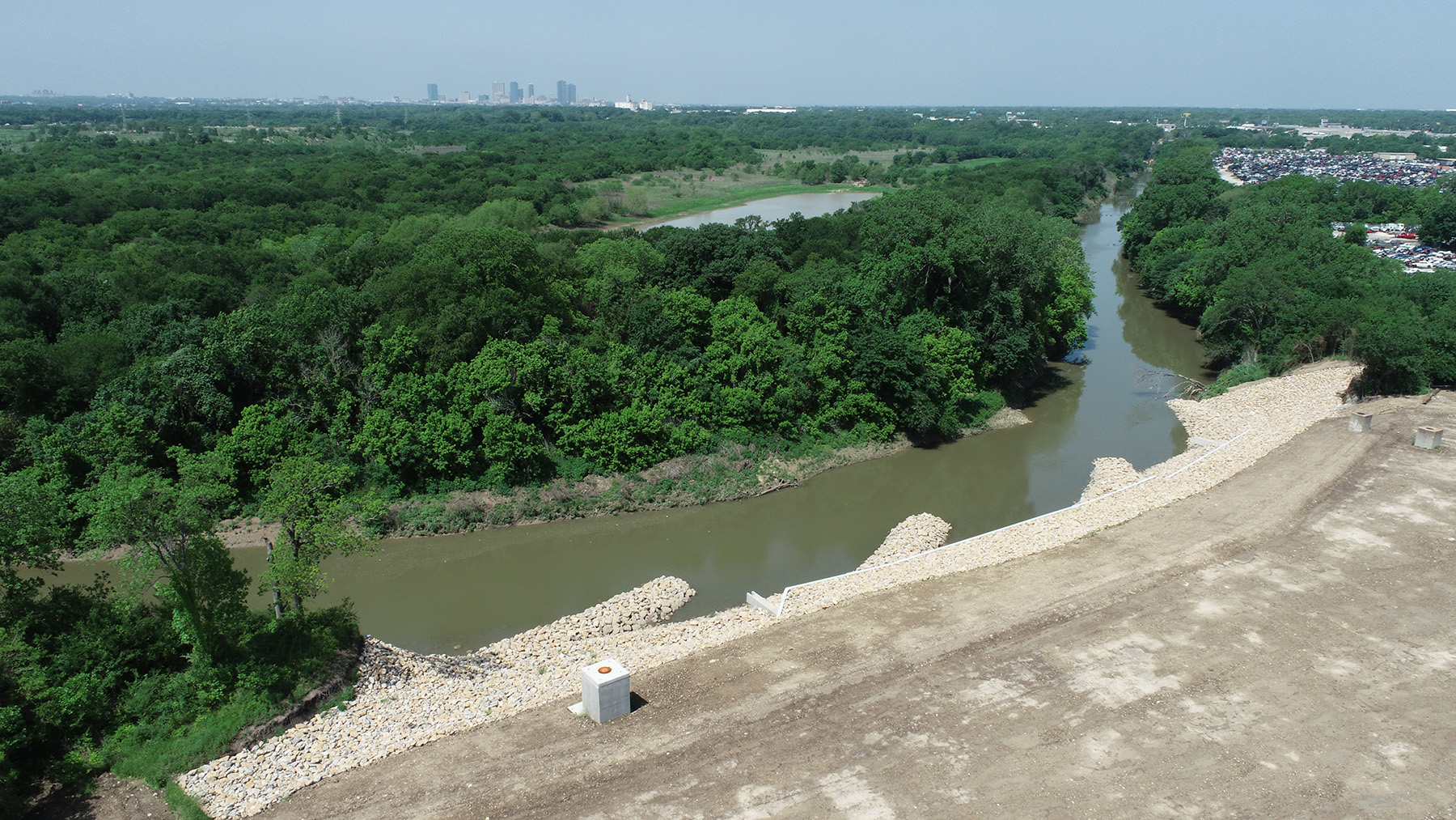 Body of water meandering through area filled with trees. on the shore are rock formations protruding into the water.