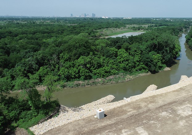 Body of water meandering through area filled with trees. on the shore are rock formations protruding into the water.