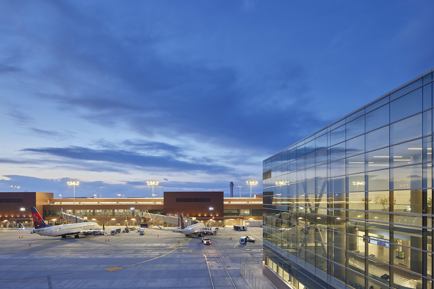 nighttime photo of an airport. there are planes and baggage retrievers shown