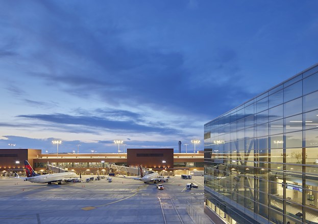 nighttime photo of an airport. there are planes and baggage retrievers shown