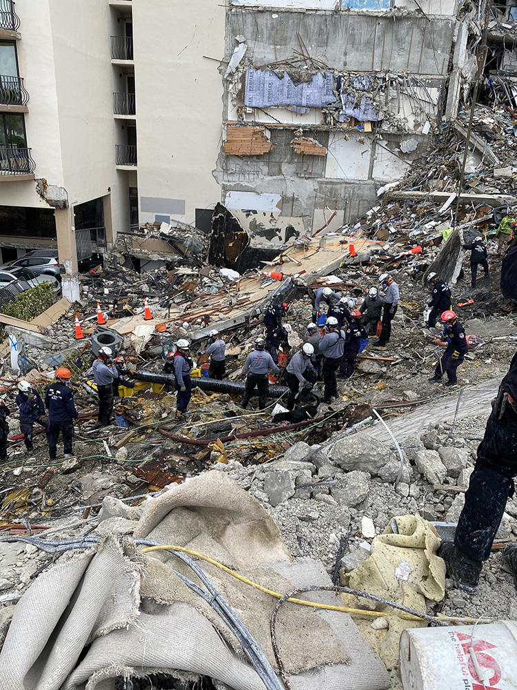 rescue workers clearing debris at the site of a building collapse.