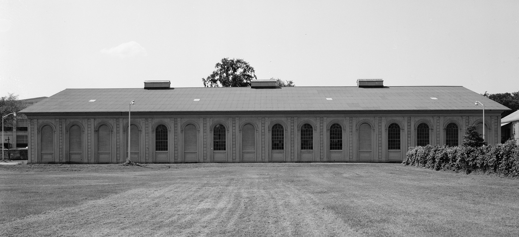 side view of a building showing many windows. there is grass in the foreground.