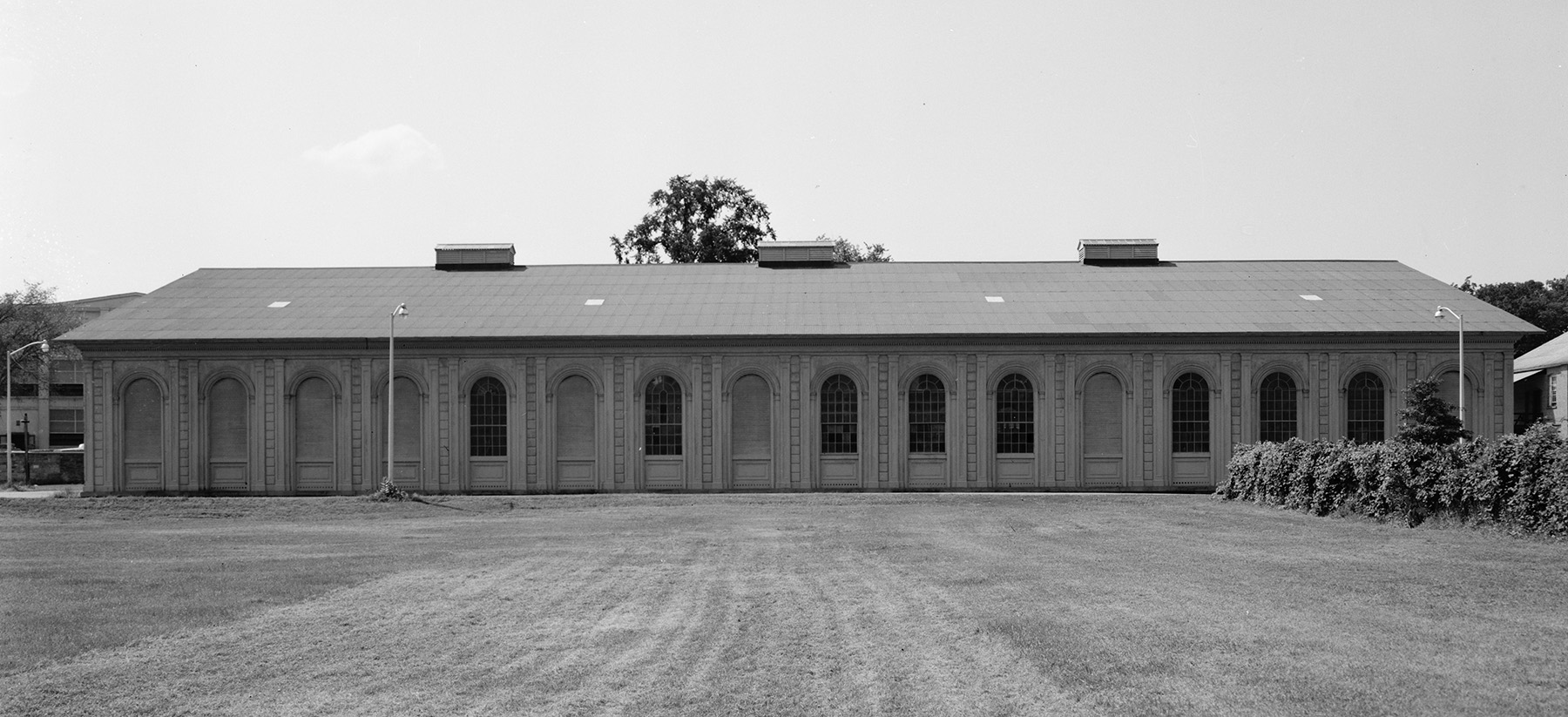 side view of a building showing many windows. there is grass in the foreground.