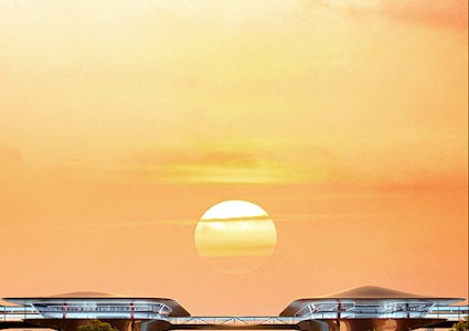 two rectangular shaped buildings on stilts are connected by a walkway. Trees are in the foreground and the sunset is in the background