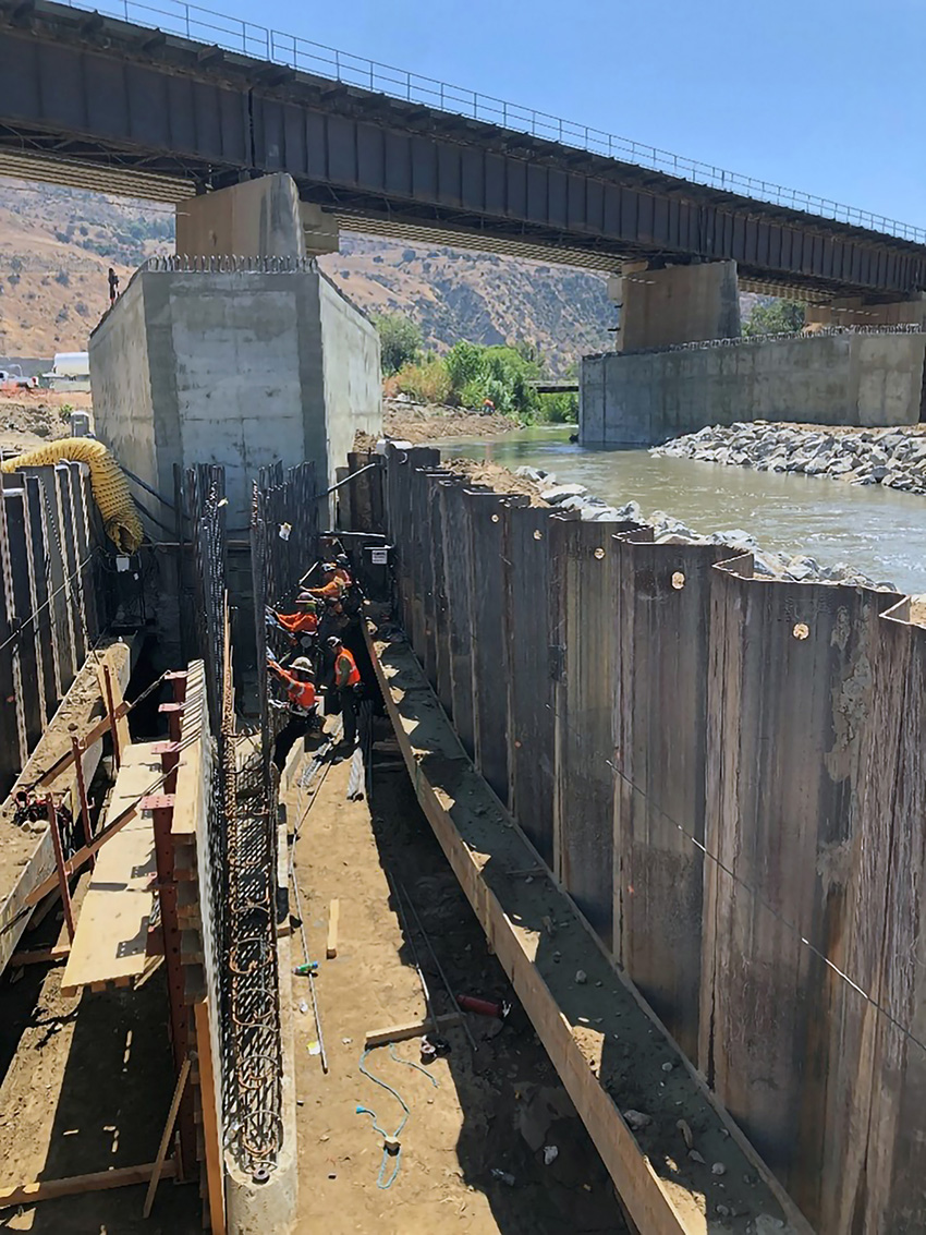 Work crew installing scour protection elements inside a sheet pile cofferdam. 