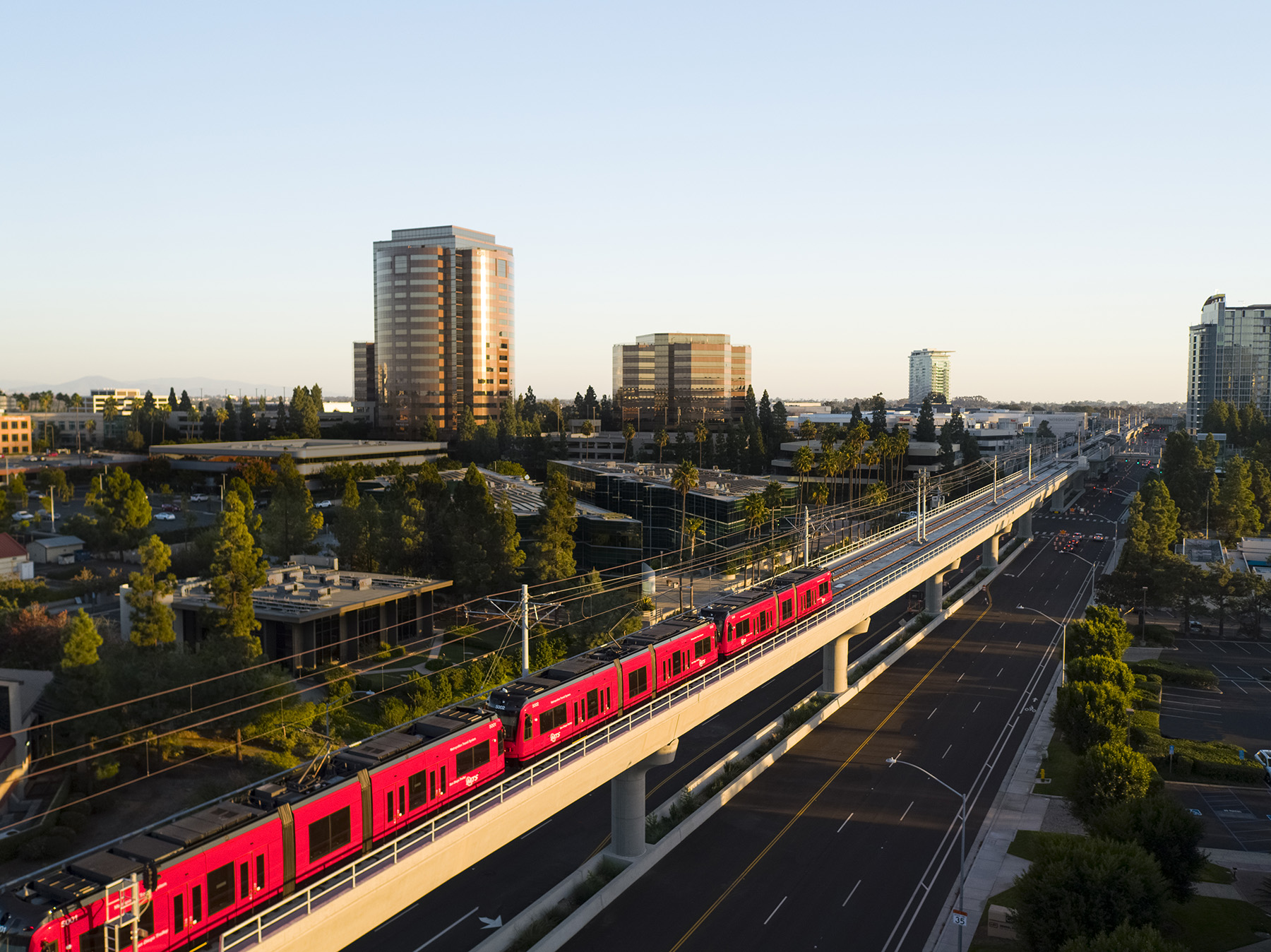 Red train moves along train tracks amidst a city scape