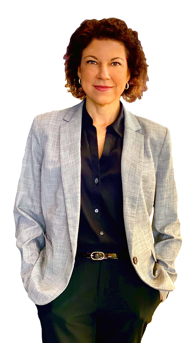 woman with curly brown hair wearing a grey jacket and black pants and shirt