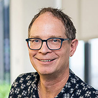 Man in black and white patterned shirt wearing glasses