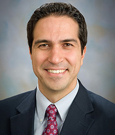 man in a black suit and maroon tie