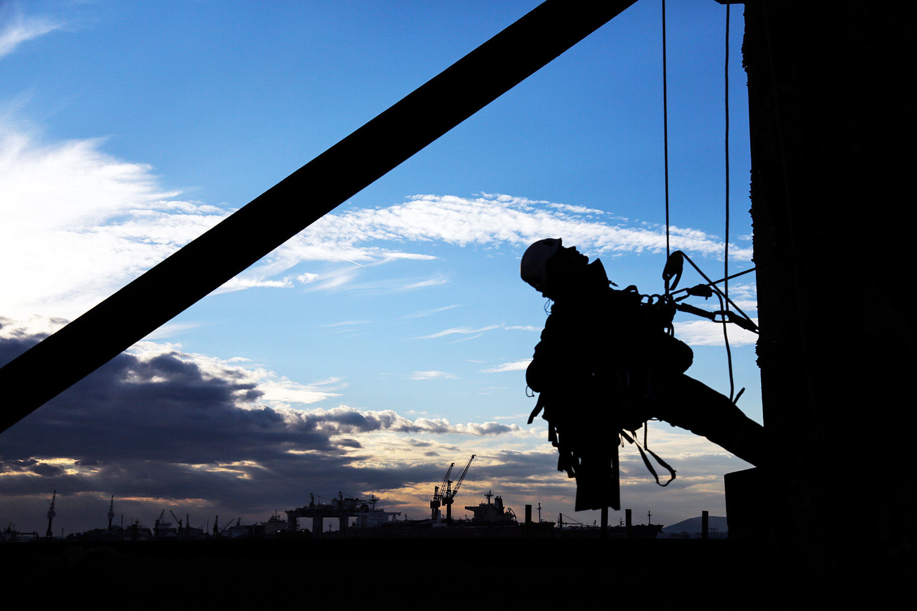 Man strapped to side of building with hooks and ropes