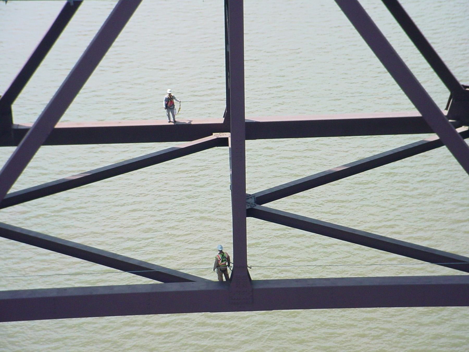 Several people are wearing safety gear are tethered to a bridge