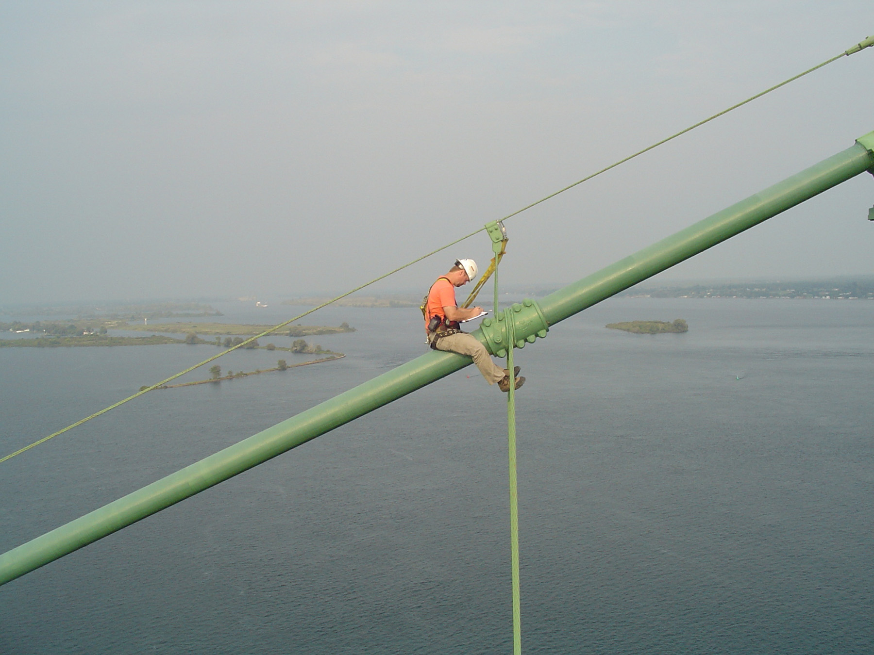 A man is strapped to a bridge as he inspects it.