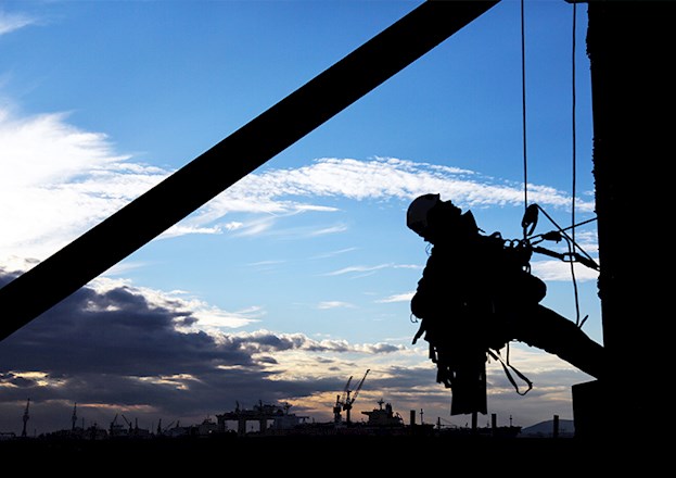 Man strapped to side of building with hooks and ropes