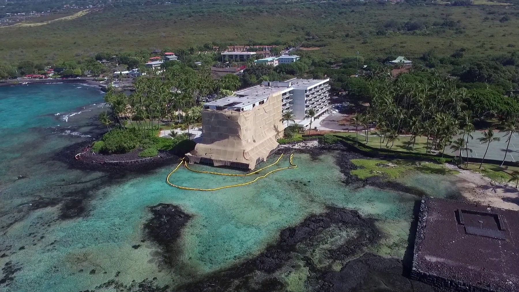 A hotel under renovation juts into a lagoon