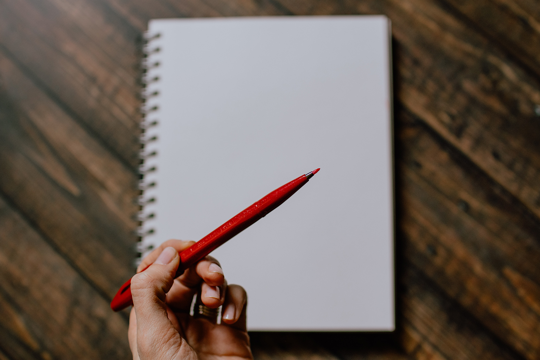 woman holding red pen hovering over blank page